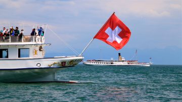 Schweizisk flagga som vinkar från en Lake Geneva paddle steamboat